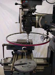ホイールを固定しリムのたわみを測定した実験器具。重りを引っ掛けて、ダイヤル測定器で測定する。 photo: sheldonbrown